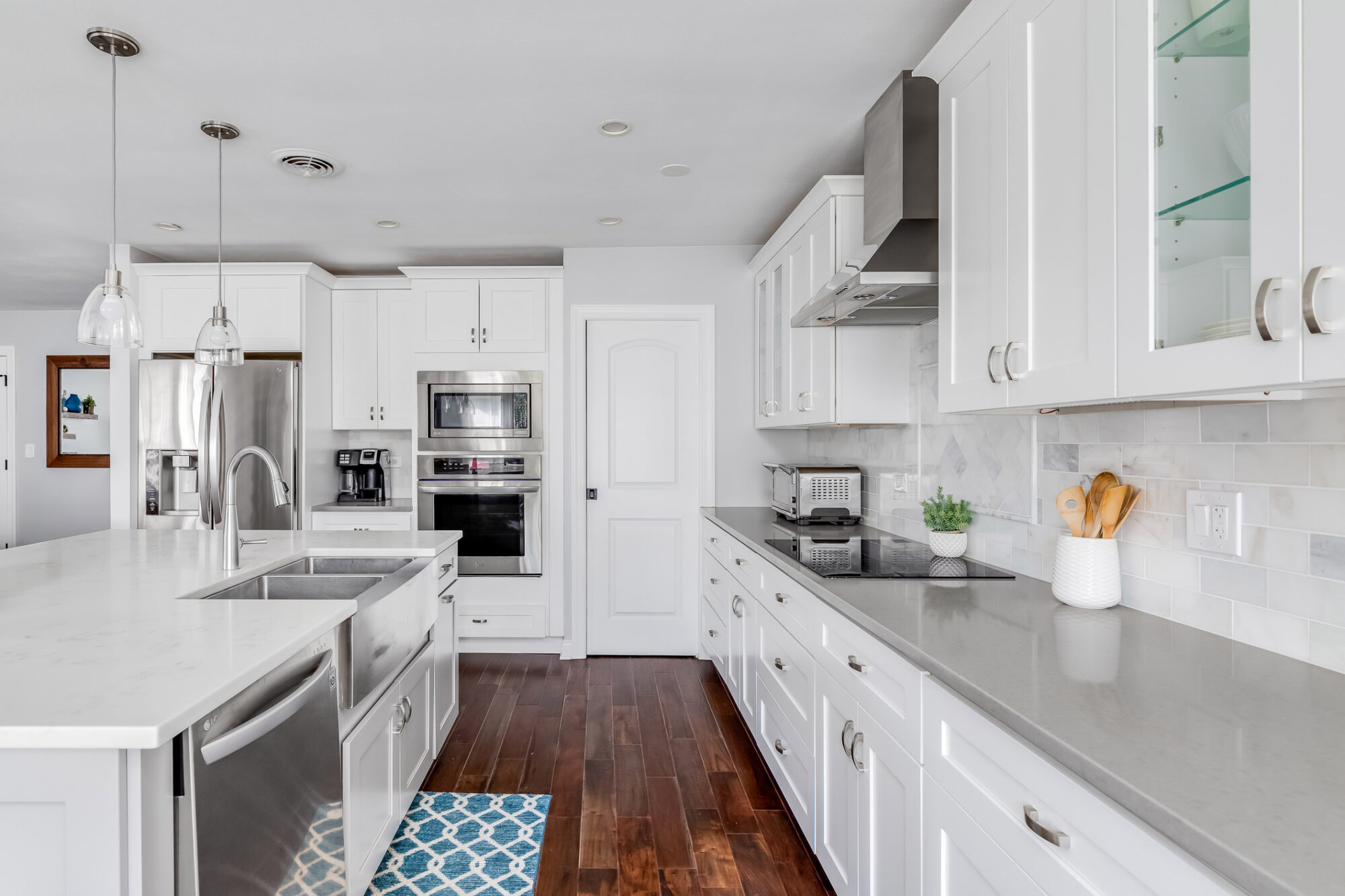 A white luxurious kitchen with stainless steel appliances. ELMHURST, IL, USA - AUGUST 4, 2020: A luxurious white kitchen with stainless steel appliances, custom tile work and hardwood floors.